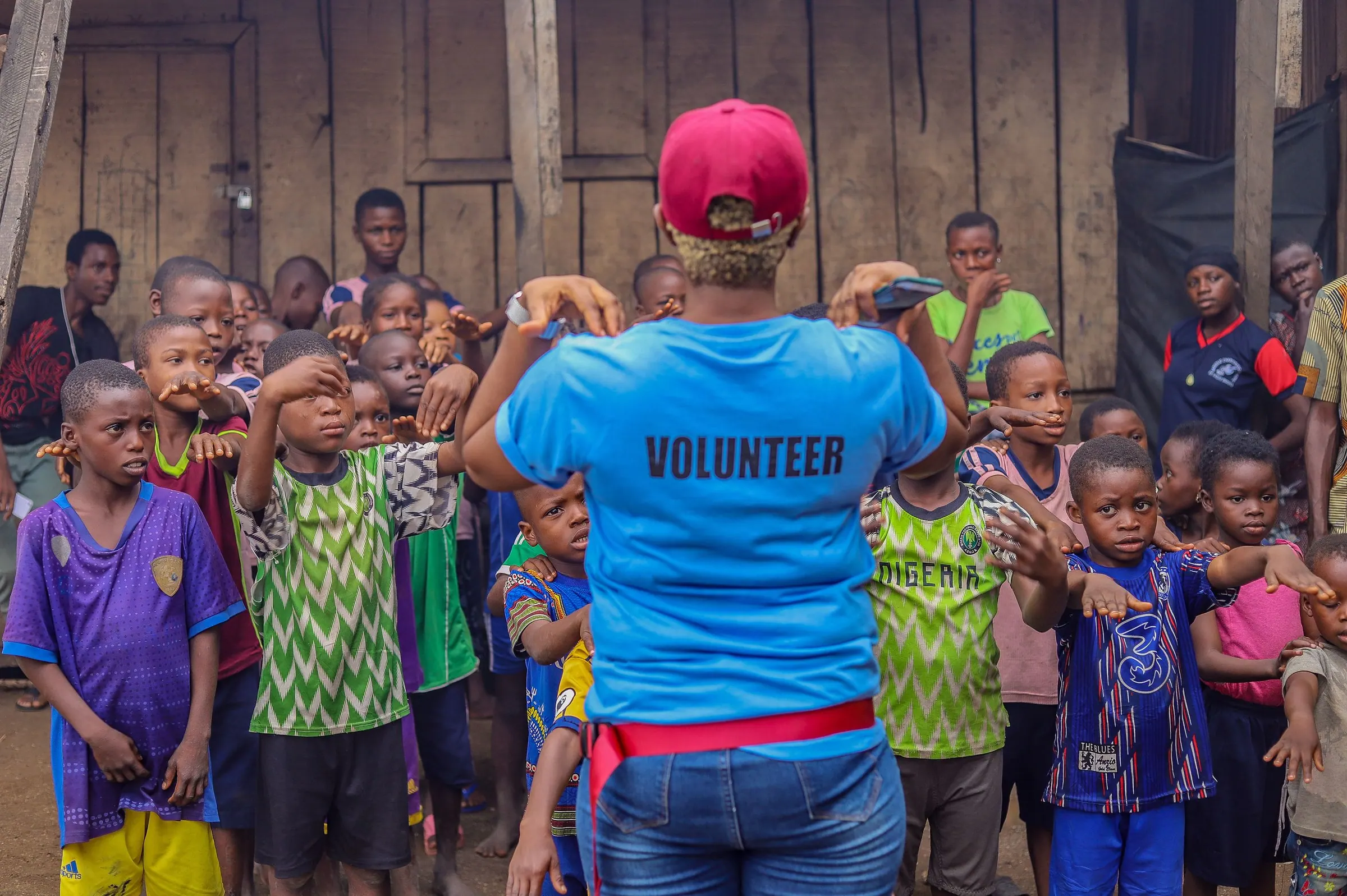 A volunteer leads a group of children in an outdoor activity